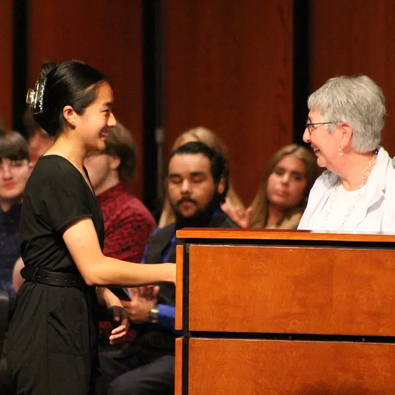 Woman presenting scholarship to student