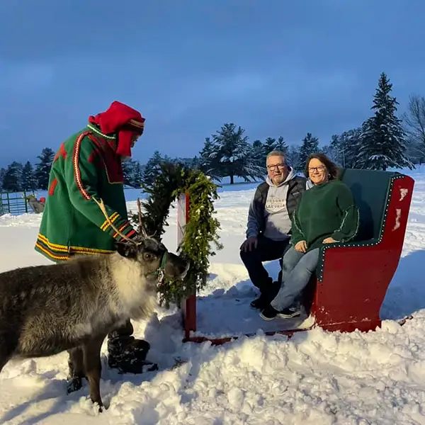 Reindeer with elf and two people in a sleigh