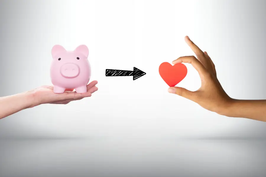 hand holding a piggy bank with arrow pointing to a hand holding a heart