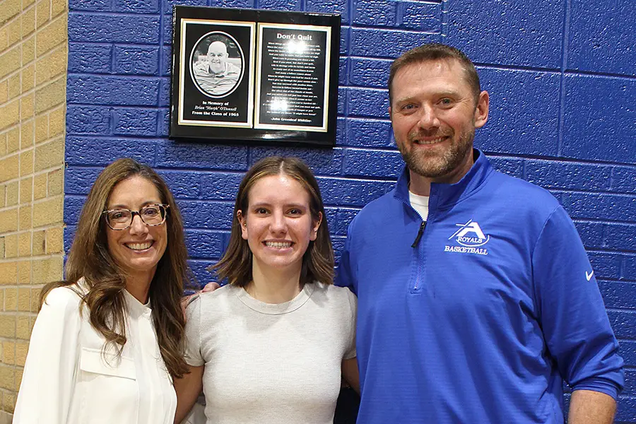 Student and two adults smiling